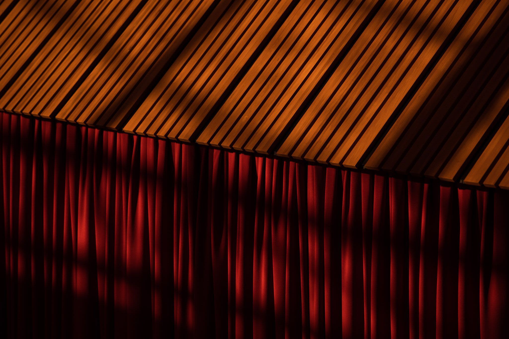 Image of red curtains falling from a timber roof